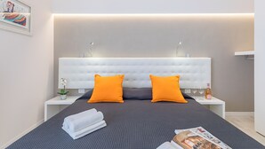 A modern bedroom with a large bed, two nightstands, a white headboard, and a small potted plant. - Appartamento Valeria by Wonderful Italy (Sirmione)
