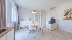 A modern kitchen with white cabinets, a dining table set for four, and a large window with curtains. - Appartamento Valeria by Wonderful Italy (Sirmione)