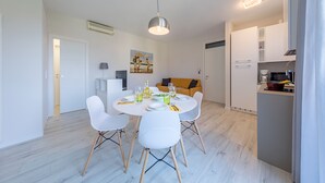 A modern dining area with a round table, white chairs, and a pendant light. - Appartamento Valeria by Wonderful Italy (Sirmione)