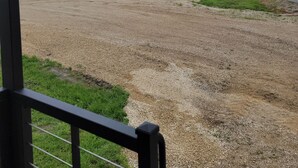 A view from inside a building looking out to a gravel field with a small shed and a silo in the distance. - Ridgetop Retreat Tiny Home, Dakota MN (Dakota)
