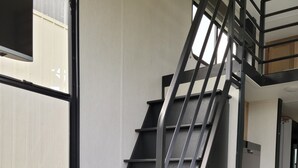 A modern interior with a black metal staircase, a washing machine, and a window with a view. - Ridgetop Retreat Tiny Home, Dakota MN (Dakota)