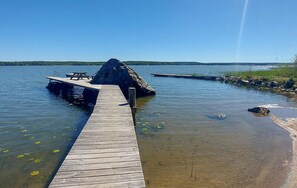 Une jetée en bois s’étendant dans une étendue d’eau calme, une table de pique-nique et une grande formation rocheuse.