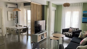 Un salon moderne comprenant un canapé, un téléviseur, une table à manger et des chaises.