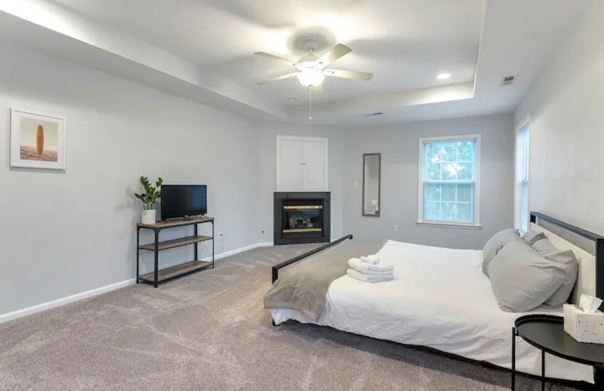 Une chambre à coucher avec un lit, une télévision, une cheminée et un ventilateur de plafond.