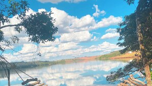 Un hamac est suspendu entre deux arbres, au-dessus d’une zone rocheuse, avec un lac en arrière-plan.