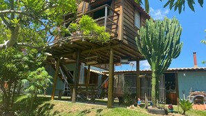 Une maison en bois dotée d’un balcon, entourée d’arbres et d’un cactus.