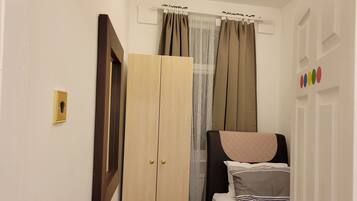 Un dormitorio con cama, armario y ventana con cortinas.