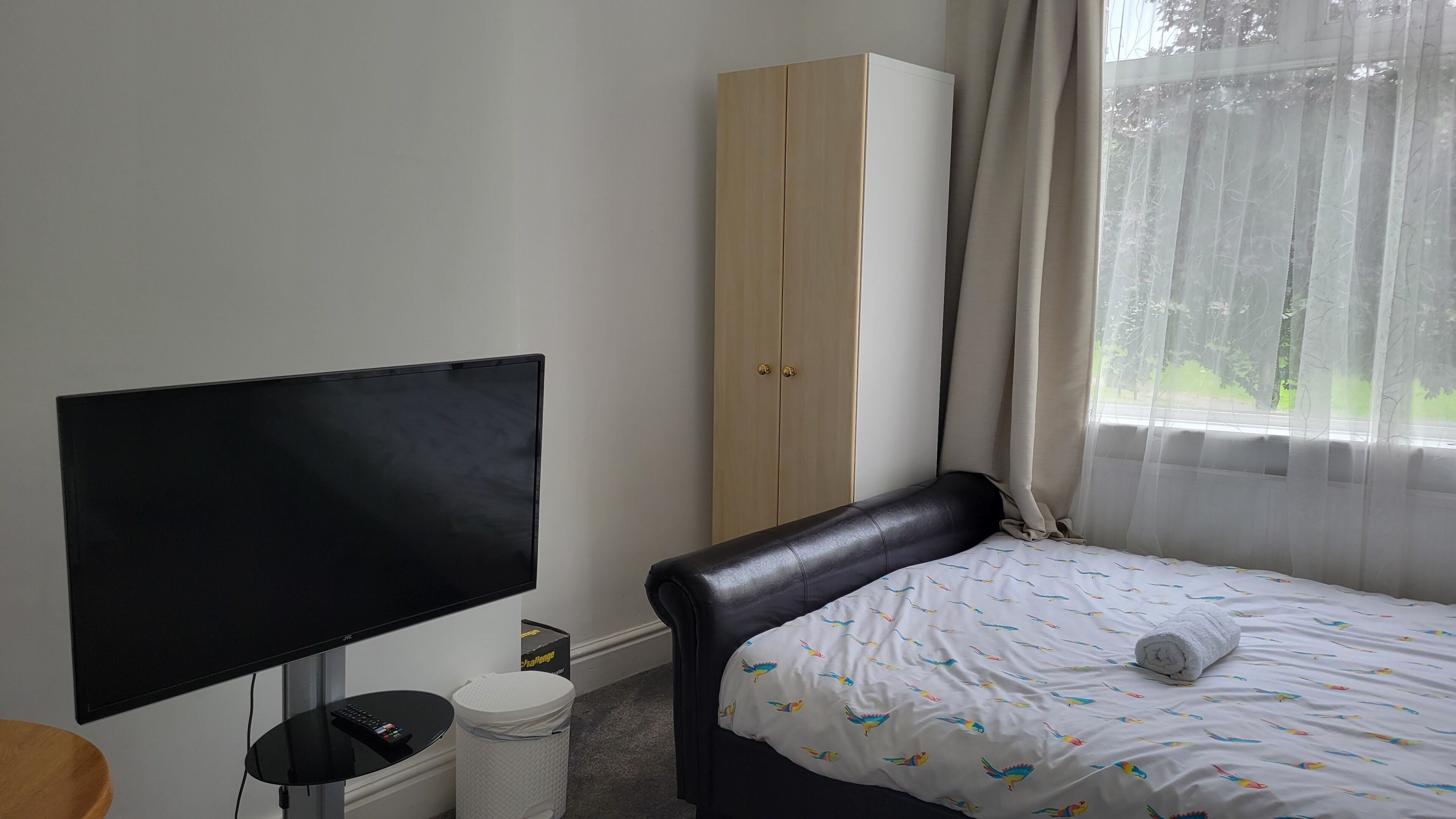 Een hotelkamer met een bed, een televisie, een kledingkast en een raam met gordijnen.