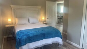 Un lit bien fait, recouvert d’une couvre-lit bleue et blanche, avec deux lampes de chevet et une tête de lit blanche.