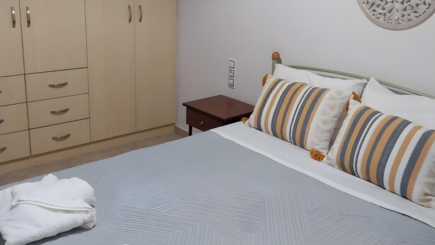 Een slaapkamer met een bed, een kledingkast, een nachtkastje en een decoratief wandobject.