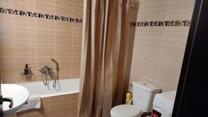 Een badkamer met een bad, toilet en wastafel.