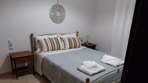 Een net opgemaakt bed met gestreepte kussens, een bedlampje en een klein houten nachtkastje.
