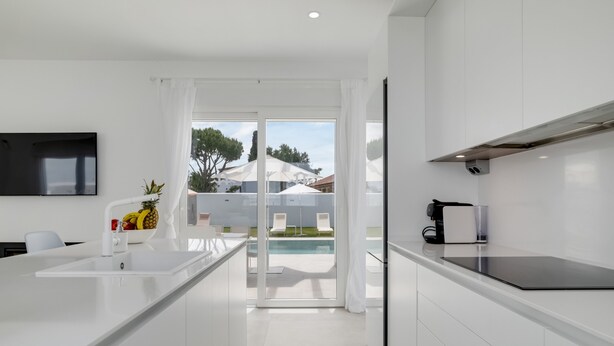 Una cocina moderna con una isla grande, horno empotrado y vistas a la zona de la piscina.
