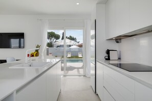 A modern kitchen with a large island, a built-in oven, and a view of a pool area.