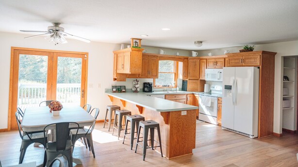 Una cocina moderna con armarios de madera, una isla central, taburetes de bar y una mesa de comedor.