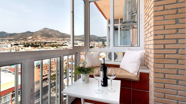 A balcony with a table, two wine glasses, a bottle, and a potted plant. - Apartment 'Apartamento Agata 2024' with Mountain View, Wi-Fi and Air Conditioning (Benalmádena)