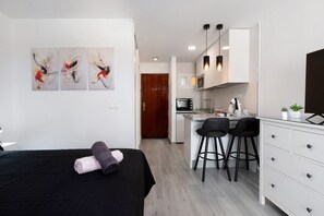 Une chambre d’hôtel moderne équipée d’un lit, d’une petite kitchenette et d’un coin repas.