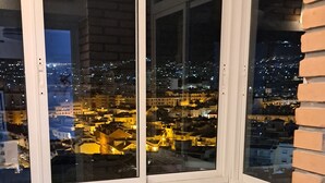 A balcony with a view of a cityscape at night, a white table, and a cushioned bench. - Apartment 'Apartamento Agata 2024' with Mountain View, Wi-Fi and Air Conditioning (Benalmádena)