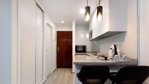A narrow kitchen with a microwave, coffee maker, and two bar stools. - Apartment 'Apartamento Agata 2024' with Mountain View, Wi-Fi and Air Conditioning (Benalmádena)
