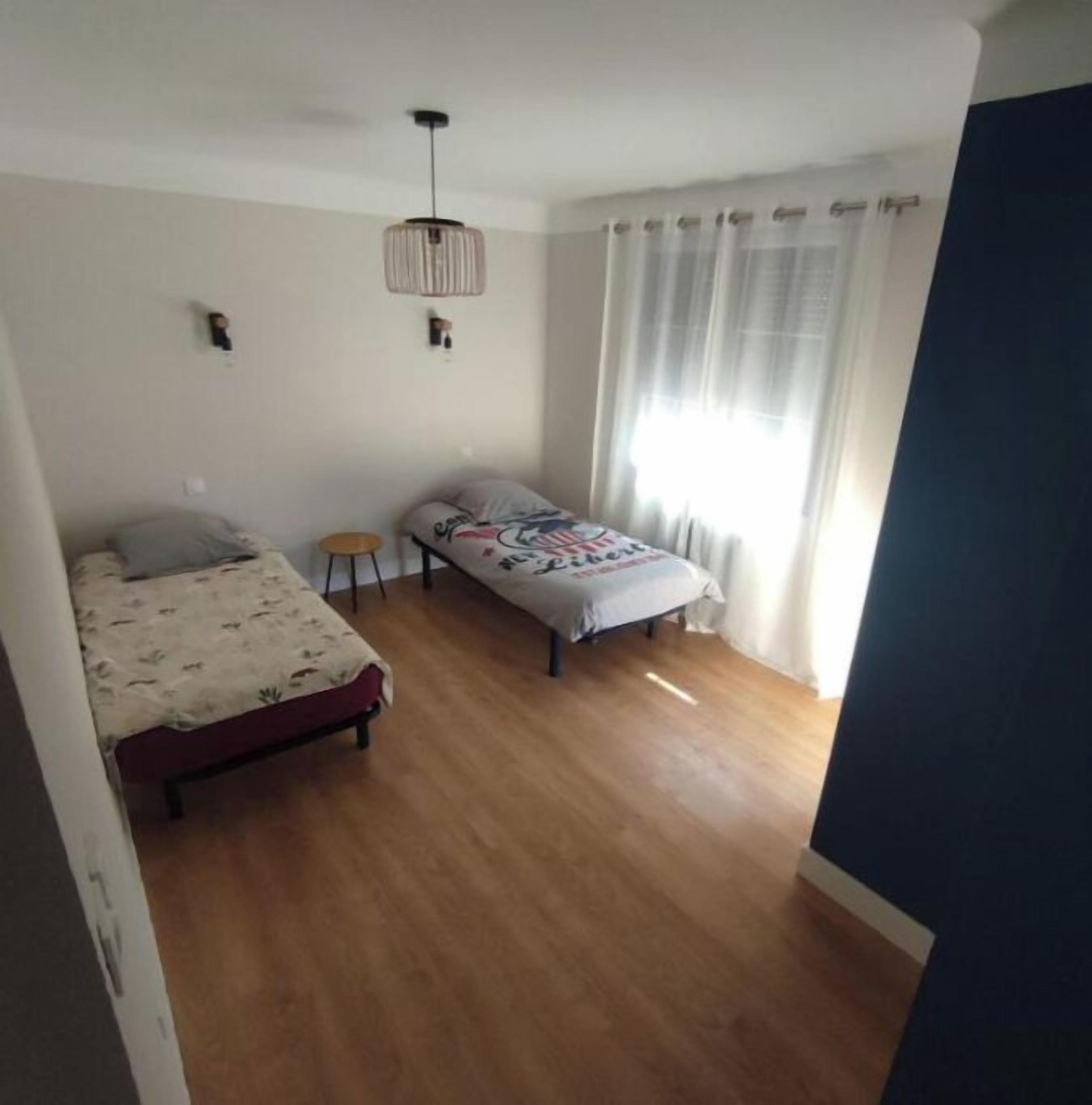 Ein Schlafzimmer mit zwei Betten, einem kleinen Tisch und einer Pendelleuchte.