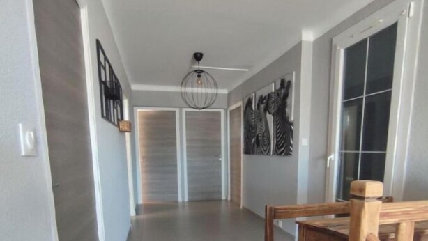 A hallway with a wooden bench, a ceiling fan, and artwork on the walls. - Large villa with all comforts, secure swimming pool, garden and barbecue (Latour bas elne)