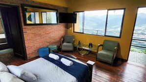 A room with a bed, a chair, a small table, and a TV mounted on the wall. - CasaView (Manizales)