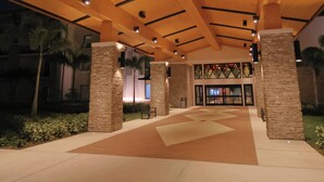 A covered walkway with wooden beams and stone pillars, leading to a building entrance. - Seminole Brighton Bay Hotel & Casino (Okeechobee)
