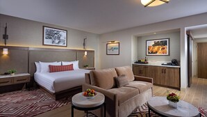 A modern hotel room with a large bed, a sofa, two small tables, and a kitchen area. - Seminole Brighton Bay Hotel & Casino (Okeechobee)