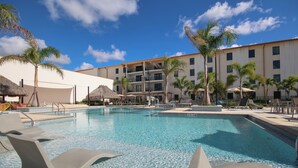 A swimming pool with lounge chairs, palm trees, and a building with balconies. - Seminole Brighton Bay Hotel & Casino (Okeechobee)