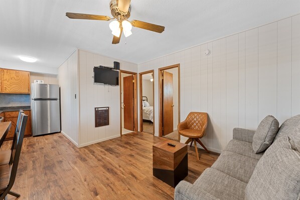 A modern kitchen with a built-in refrigerator, wooden flooring, and a ceiling fan.