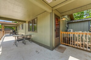 A covered patio area with a table and chairs, a wooden deck, and a door leading to an outdoor space. - 2BR Duplex Cabin w/Community Pool + Boat dock (Branson West)