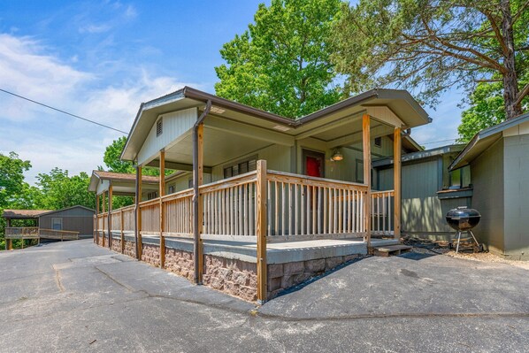 A two-story house with a porch, a red door, and a barbecue grill in the yard. - 2BR Duplex Cabin w/Community Pool + Boat dock (Branson West)