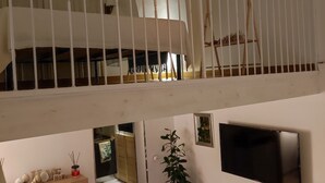 Un interior amb diversos nivells, una escala, un televisor penjat a la paret i una banca de fusta.