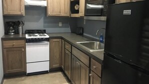 Una cocina con armarios de madera, estufa, lavamanos y refrigerador.