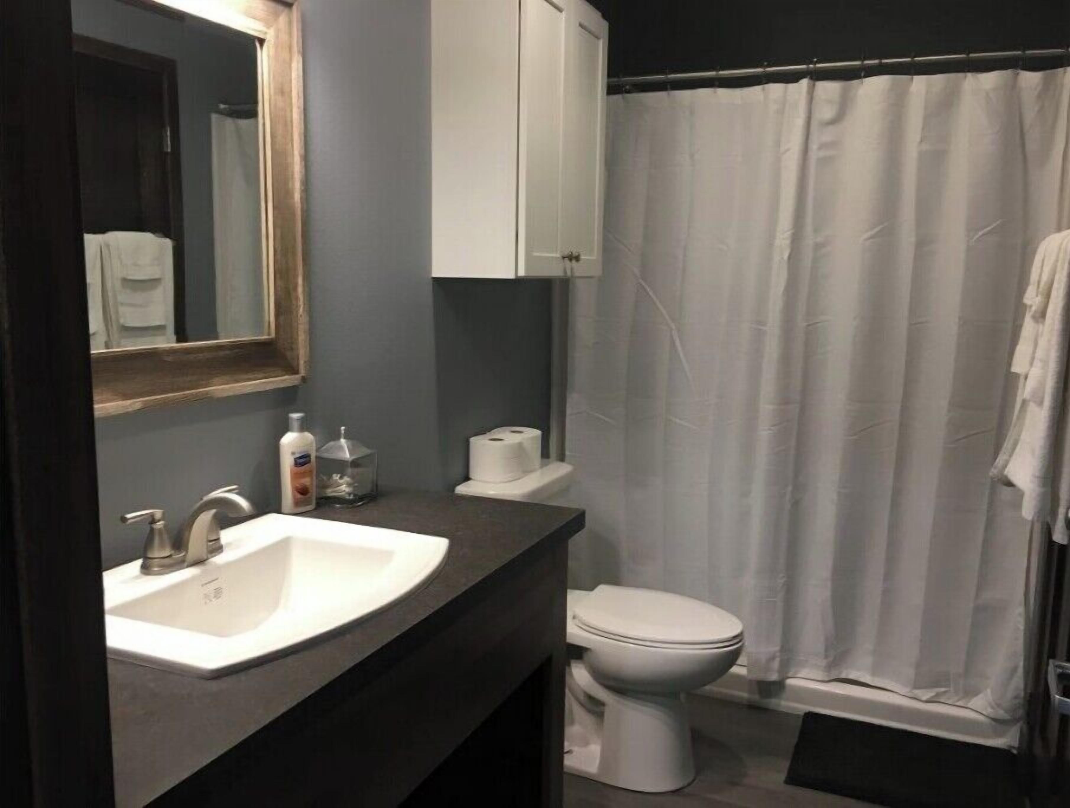 Un baño con un lavamanos blanco, un inodoro y una cortina de ducha.