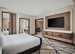 A hotel room with a large bed, a TV mounted on the wall, a bathroom with a mirror, and a patterned carpet. - Hard Rock Hotel & Casino Ottawa (Ottawa)