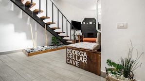 Un interior moderno con una escalera, una chimenea de piedra y un banco de madera con la inscripción 'BODEGA CELLAR CAVE'.