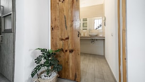 Puerta corredera de madera que da a un baño con lavamanos y espejo.