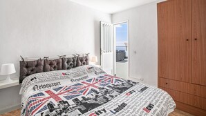 Un dormitorio con cama, armario, ventana y vista al cielo.