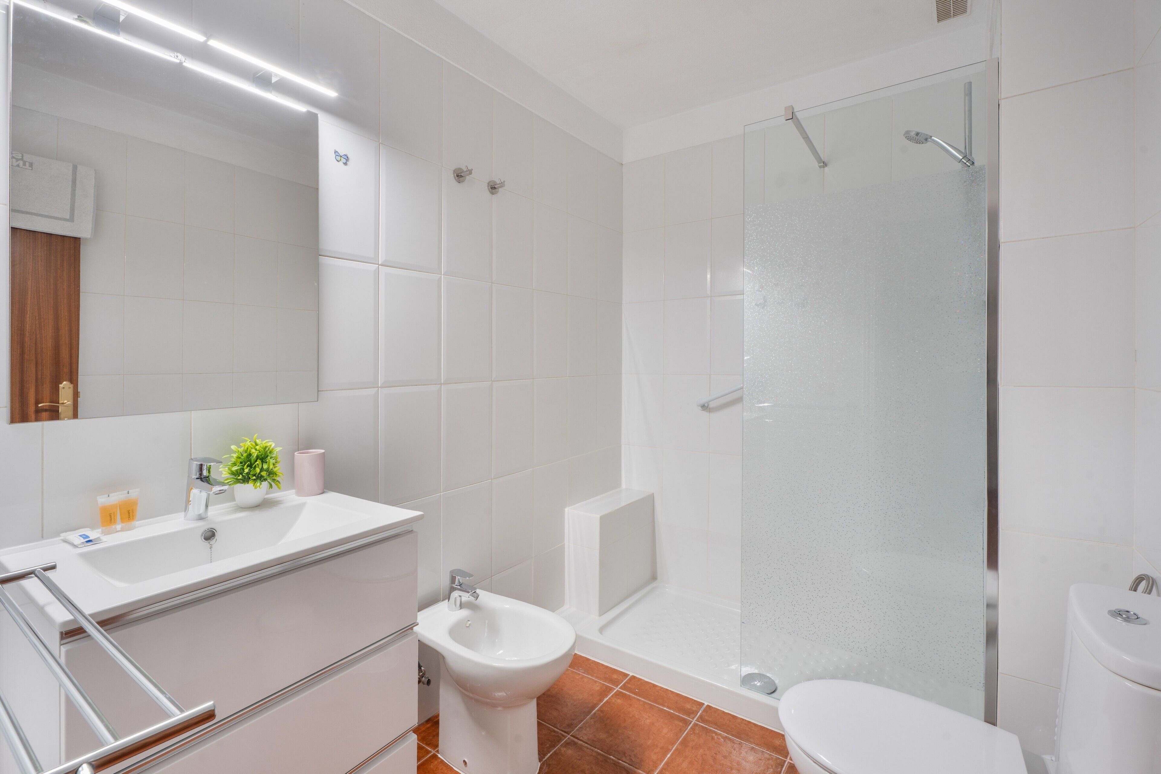 Un baño moderno con cabina de ducha de vidrio, un lavamanos blanco y un bidé.