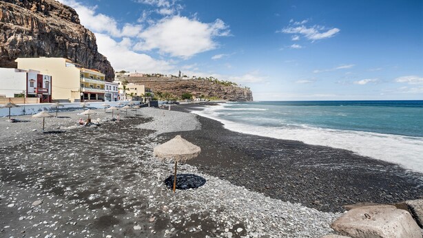 Una zona costera con una playa rocosa, edificios y un acantilado.