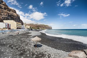 Una zona costera con una playa rocosa, edificios y un acantilado.