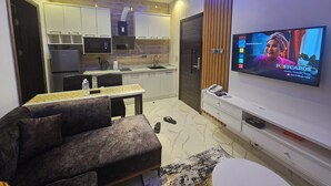 A modern living room with a sofa, TV, and kitchen area.
