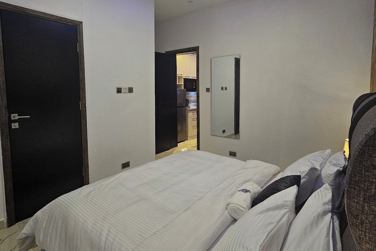 Ein Hotelzimmer mit Bett, Tür, Spiegel und Deckenleuchte.