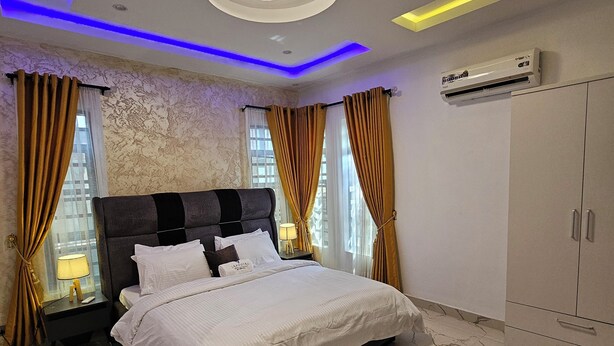 A modern bedroom with a large bed, marble flooring, and a ceiling with recessed lighting.