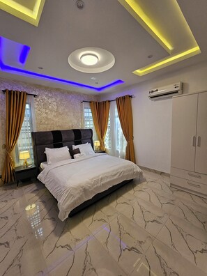 A modern bedroom with a large bed, marble flooring, and a ceiling with recessed lighting. - Sapphire Residences by Crystal Magodo (Lagos)