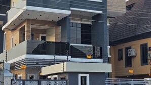 A multi-story residential building with a modern design, featuring balconies, large windows, and a gated entrance.