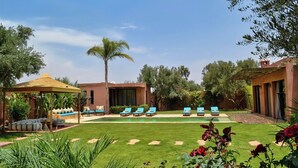 A poolside area with lounge chairs, a gazebo, and a well-maintained lawn. - Domaine Homa in Marrakech: A Haven of Peace and Relaxation (Marrakech)