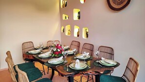 A dining area with a wooden table set for six, surrounded by wicker chairs, and a decorative wall with mirrors. - Domaine Homa in Marrakech: A Haven of Peace and Relaxation (Marrakech)