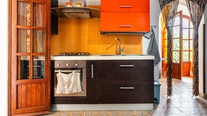 Eine Küche mit Herd, Backofen und orangenen Schränken.